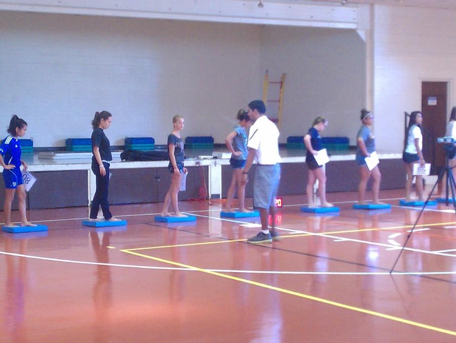 Students participate in a balance test in the gymnasium. 