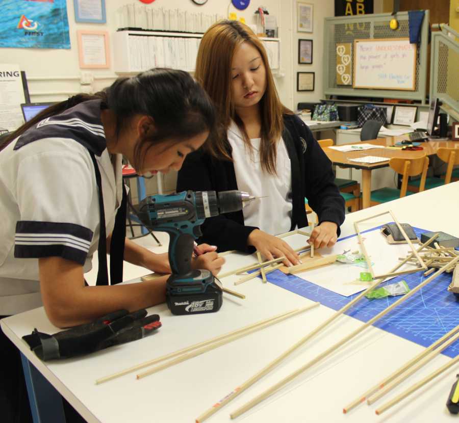 Junior Jennifer Pang and senior Sara Tashima work on measurements to construct a bridge in Introduction to Engineering class.