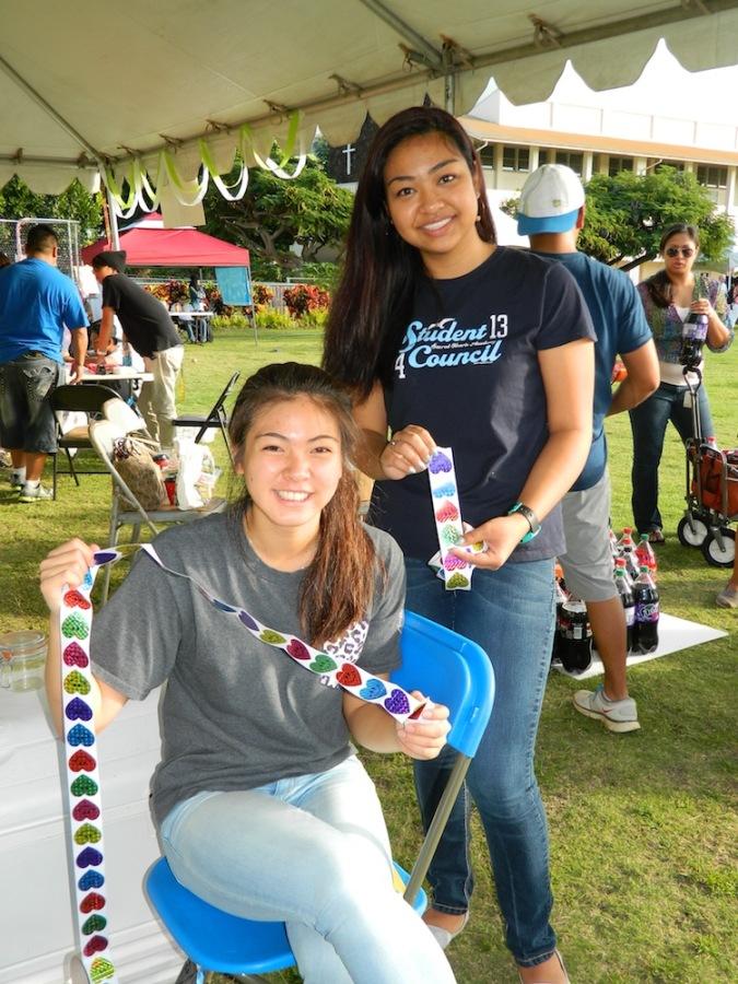 Student council members, Pamela Nishida and Caroline Kikkawa, passed out stickers to participants at their game booth, Lancer Luck, at the Year of Faith celebration.