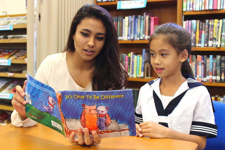 Junior Mahealani Sims-Tulba reads her book to second grader Leilani Freitas. Its Okay To Be Different depicts a story of how one bird overcomes bullying. Photo by Rochell Ann Agapay.