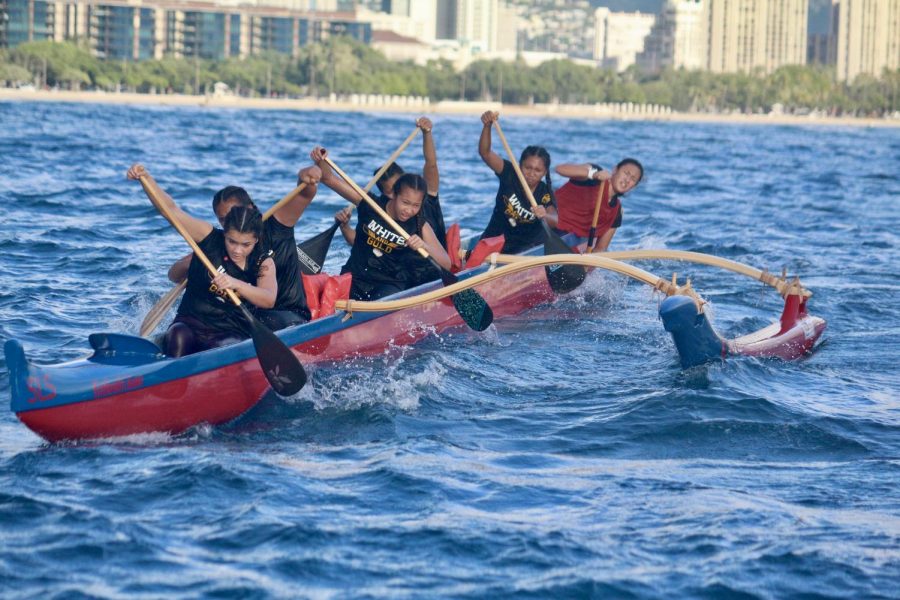 Sacred Hearts Academy’s varsity team powers through its first 3-mile paddling race from Magic Island to Kewalo Basin earlier in the season. Steersman and senior Kauilani Murakami (back) is preparing to maneuver the canoe around the turn buoys. Photo by Rebecca Meyer.