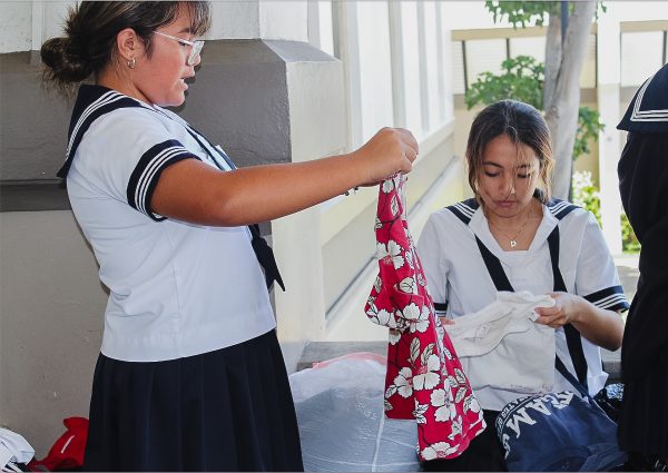 (Left to right) Academy students Tiarelei Keanu and Kaila Teves folding donated clothes for Maui fire victims. They volunteered at today’s donation drive, which collected enough items to fill three vans and a truck. Photo by Keira Wheeler.