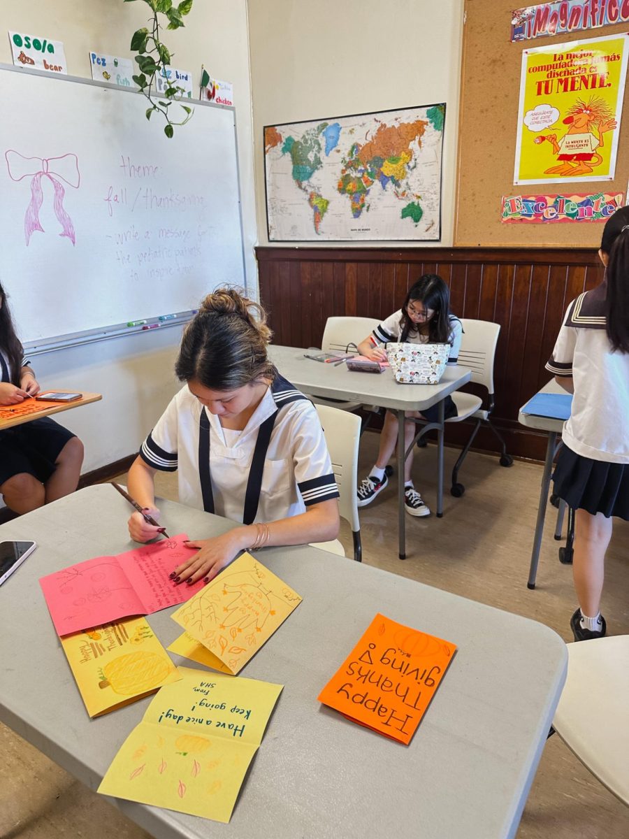 Senior Keira Mendonca and Junior Liana Seo write heartfelt cards for the children at Kapiolani Medical Center for Women and Children. Photo courtesy by Tehana Maurice