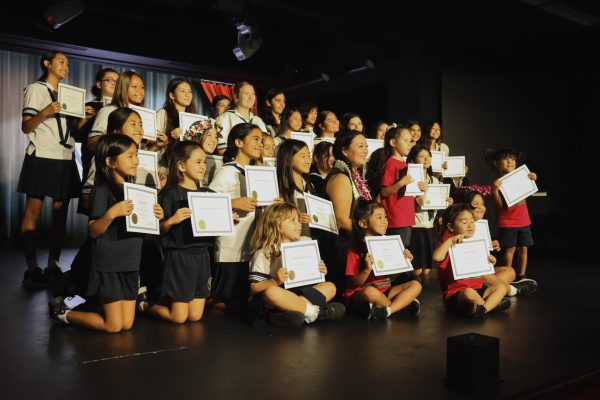 (Center) Claire Tarumoto, vice president and grants administrator for Bank of Hawaii, smiles for the camera as recipients of the McInerney Foundation scholarship hold their certificates. The grant, established in 2020, provides tuition assistance for students in preschool through grade 12. Photo by Bailey Leong.