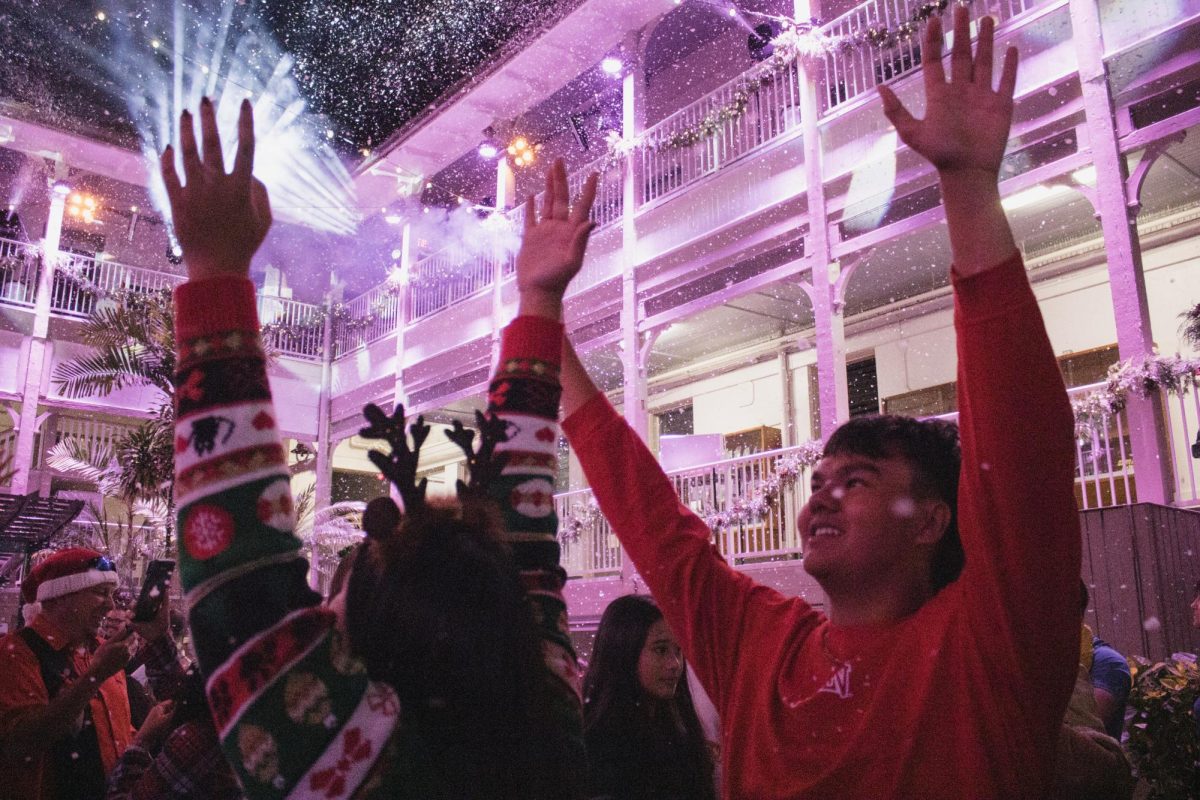 A community member smiled under the falling artificial snow, an uncommon sight in Hawaii, where winter nights are typically warm and shaped by ocean breezes rather than snowfall. The scene transformed the courtyard into a winter-themed setting, giving families and students the chance to experience a familiar holiday tradition in a tropical environment.
