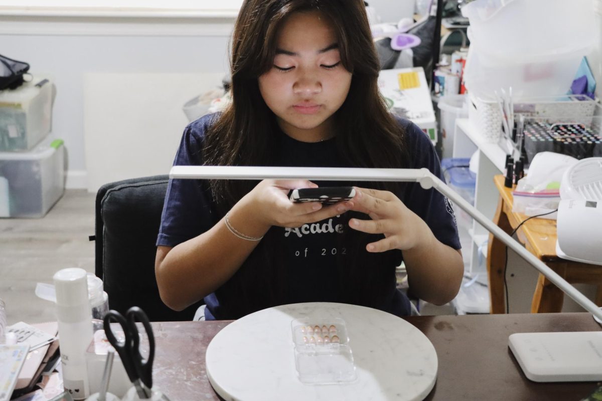 Academy junior Karys Shimizu takes photos of the press-on nails she designed to post on her business' social media account. She uses the platform primarily to post her work and communicate with customers through direct messaging. Photo courtesy of Karys Shimizu.