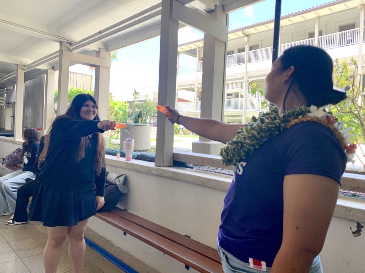 Seniors Rayne Botelho-Ichimura and Marissa Thompson participate in a duel during Senior Splashin' by the library. Photo by Katie Kaoihana